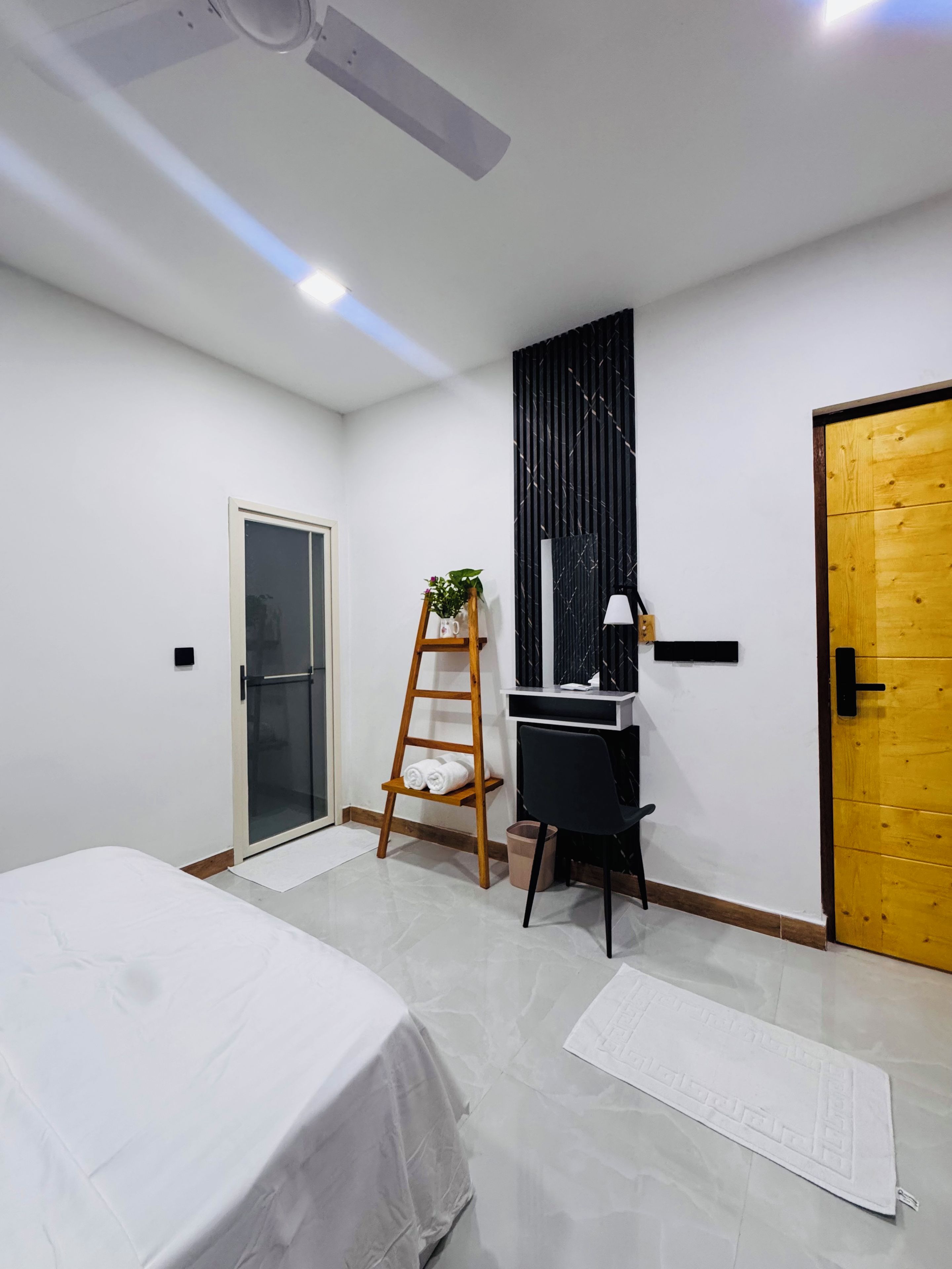 Ein modernes Schlafzimmer mit Bett, Schreibtisch, einer Wendeltreppe, einer Tür und einem Deckenventilator.