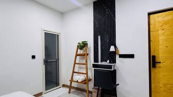 Ein modernes Schlafzimmer mit Bett, Schreibtisch, einer Wendeltreppe, einer Tür und einem Deckenventilator.