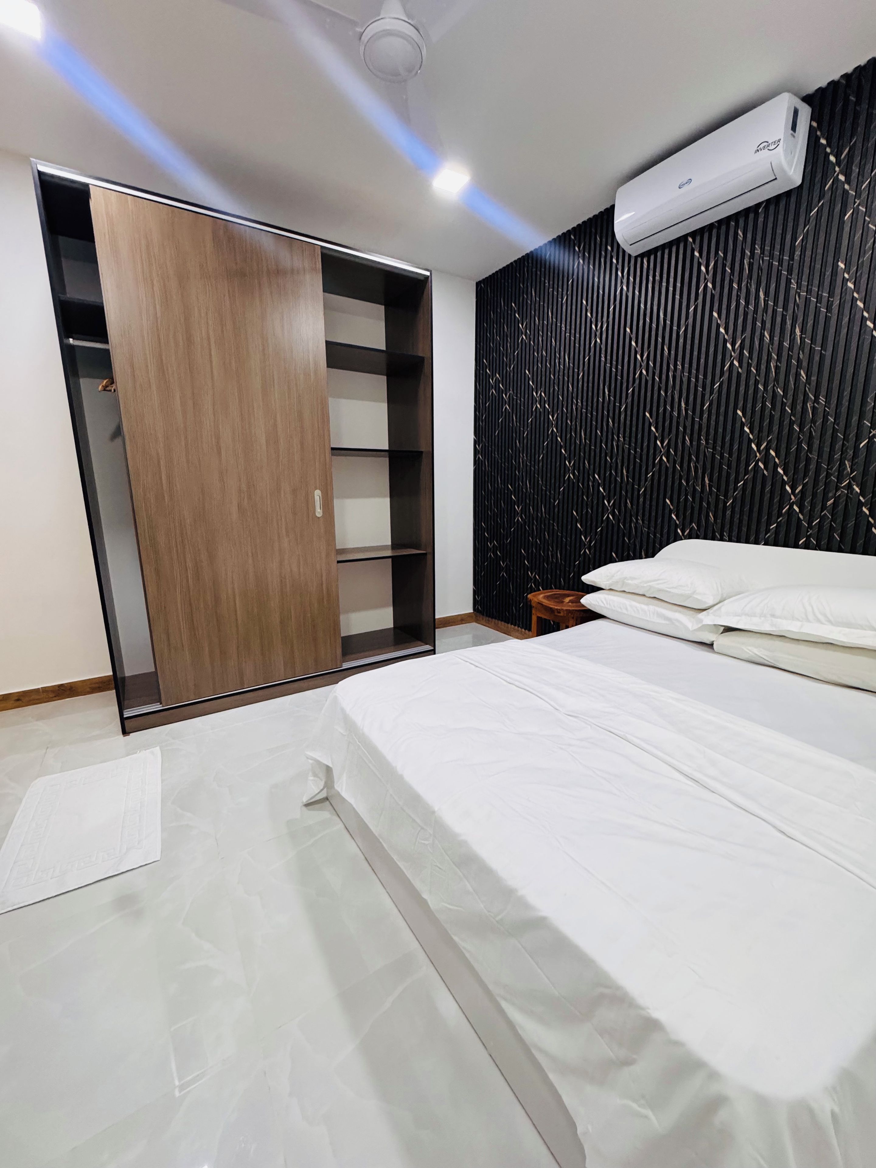 Un dormitorio con cama, armario, una mesita y aire acondicionado instalado en la pared.