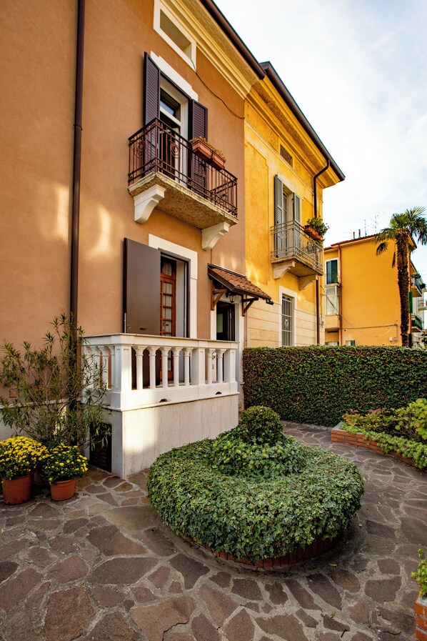 A building with a stone-paved courtyard, a white balustrade, and a neatly trimmed hedge. - Apartment Vibes Verona (Verona)