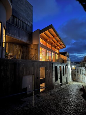 Un bâtiment moderne avec une façade en bois, un balcon et une cour pavée.