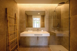Une salle de bain moderne avec un grand lavabo, un miroir et une douche en verre.