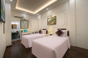 A hotel room with two beds, a bathroom, a mirror, and a painting on the wall. - Bastra Classy Hotel (Hoan Kiem Ward)