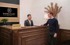 A reception desk at the BASTRA CLASSY HOTEL with a sign indicating the reception area. - Bastra Classy Hotel (Hanoi)