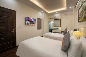 A hotel room with two beds, a TV, a mirror, a desk, and a lamp. - Bastra Classy Hotel (Hoan Kiem Ward)