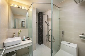 A modern bathroom with a glass-enclosed shower, a white sink, and a toilet. - Bastra Classy Hotel (Hoan Kiem Ward)