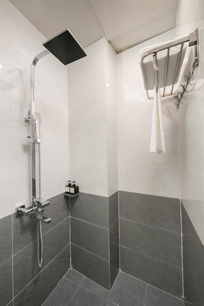 A modern shower with a handheld showerhead, a wall-mounted towel rack, and a small shelf with toiletries. - Bastra Classy Hotel (Hoan Kiem Ward)