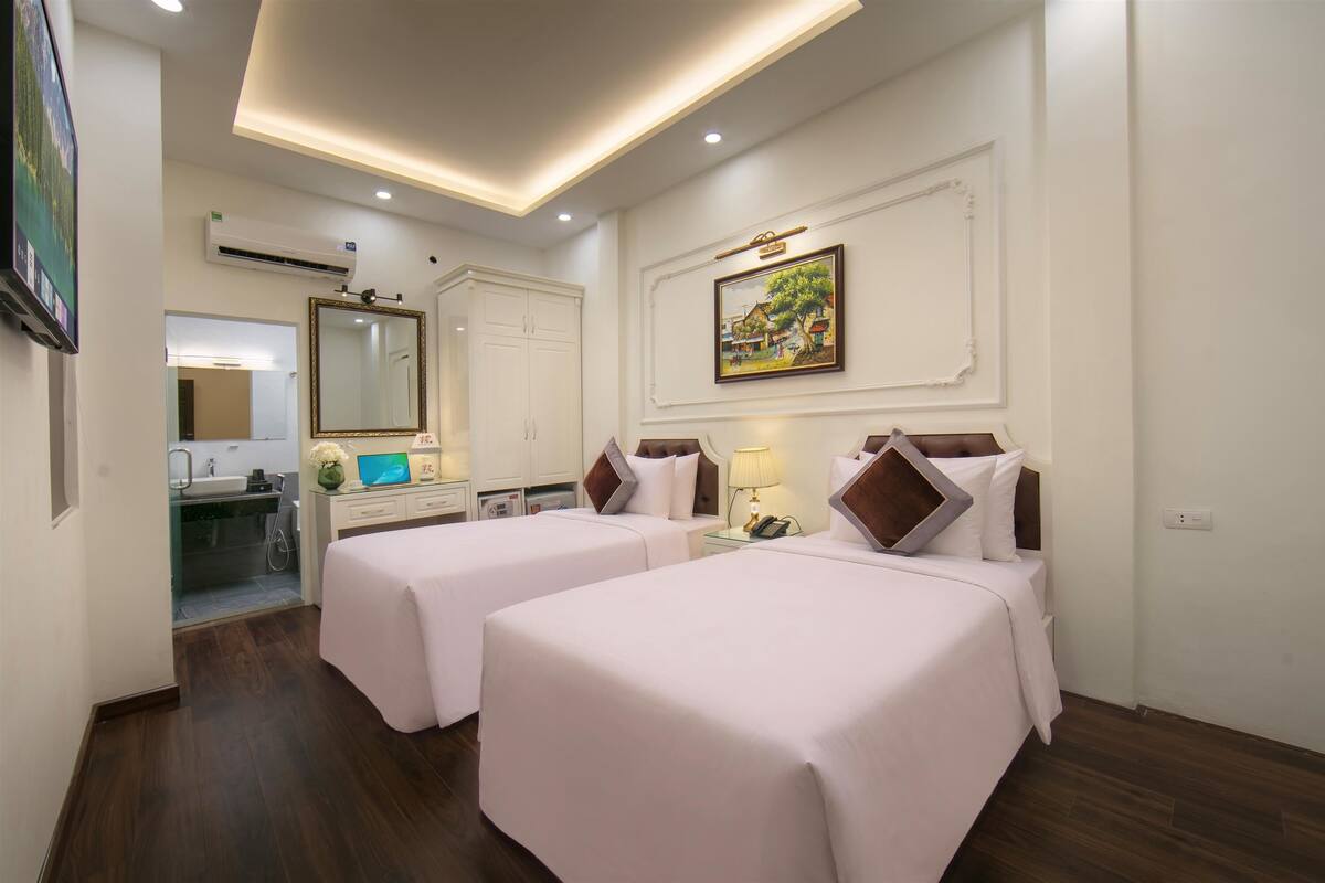 Habitació d'hotel amb dos llits, un bany, un mirall i un quadre a la paret.