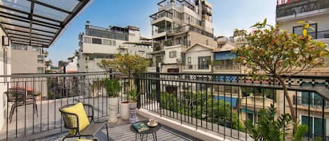 A balcony with outdoor furniture, potted plants, and a view of surrounding buildings.