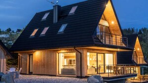 Ein modernes Haus mit Satteldach, großen Fenstern und einem Balkon.