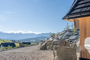A wooden building with a sloped roof, a gravel driveway, and a view of distant mountains. - Home With a Bathtub Overlooking the Mountains (Bukowina Tatrzanska)