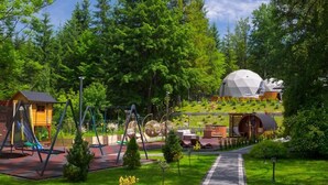 A playground with swings and slides, a dome-shaped building, and a paved pathway. - Glamp Mała Łąka Jacuzzi & Sauna Zakopane (Zakopane)