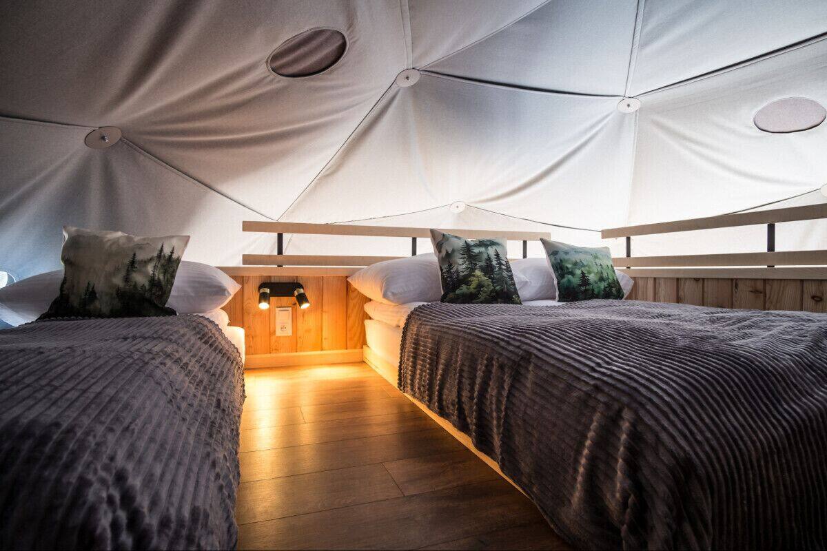 Habitación tipo tienda de campaña con dos camas, cada una con almohada y cabecero.
