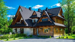 A wooden log cabin with a sign 'WILLA MALA LARA,' a paved driveway, and a well-maintained garden. - Glamp Mała Łąka Jacuzzi & Sauna Zakopane (Zakopane)