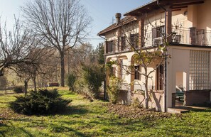 Ein zweistöckiges Gebäude mit einem Balkon, einem kleinen Garten und einer Bank.