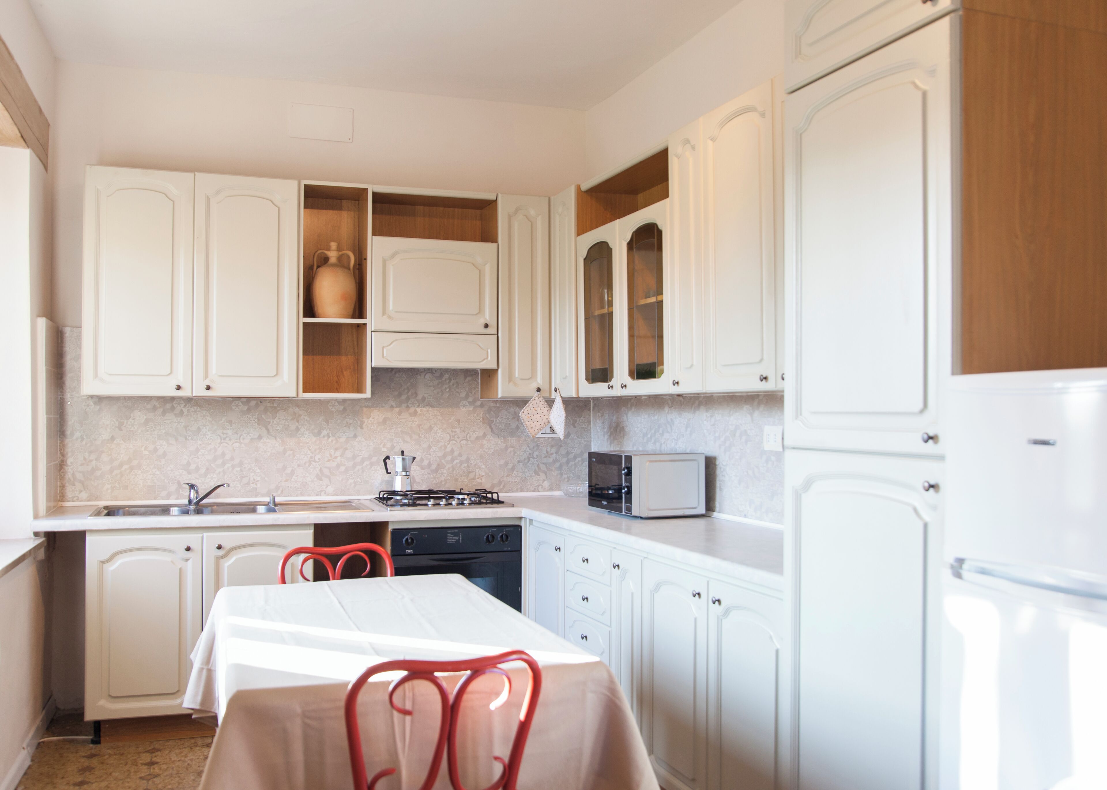 A kitchen with white cabinets, a stove, a microwave, and a table with chairs.