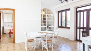 Een eetgedeelte met een ronde tafel, witte stoelen, een schaakbord en een groot rondboogvenster.