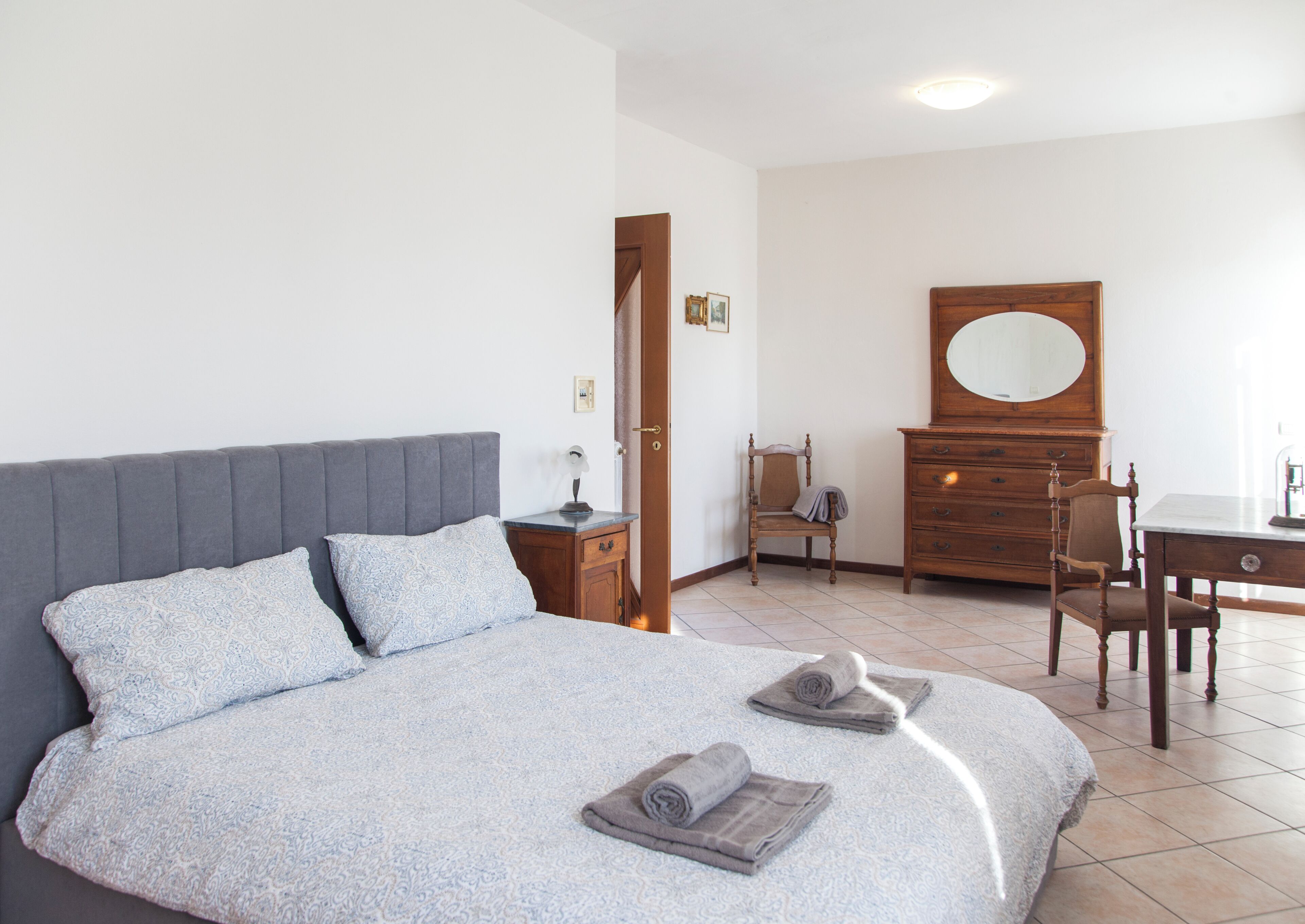 Un dormitorio con una cama, un aparador de madera, una silla y un escritorio.