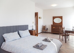 Ein Schlafzimmer mit einem Bett, einem Holzschrank, einem Stuhl und einem Schreibtisch.