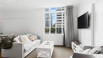A modern living room with a white sofa, a coffee table, and a TV mounted on the wall.
