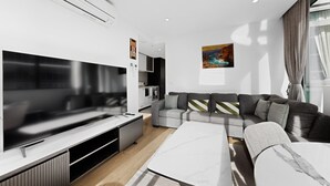 A modern living room with a flat-screen TV, grey sofa, and a white coffee table. - Elevated 2-bed Stay Steps From Crown (Melbourne)