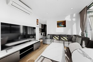 A modern living room with a flat-screen TV, grey sofa, and a white coffee table. - Elevated 2-bed Stay Steps From Crown (Melbourne)