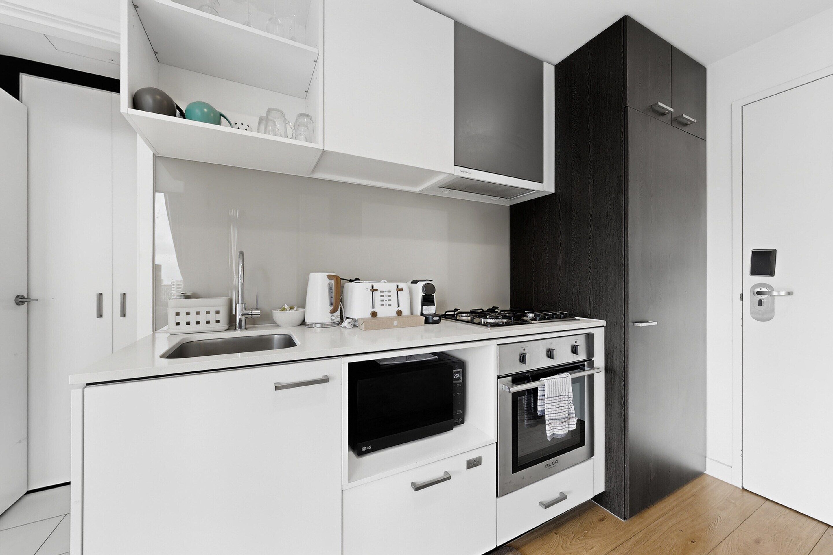 Une cuisine moderne avec des meubles blancs, un four à micro-ondes encastré, un four traditionnel et une cuisinière à gaz.