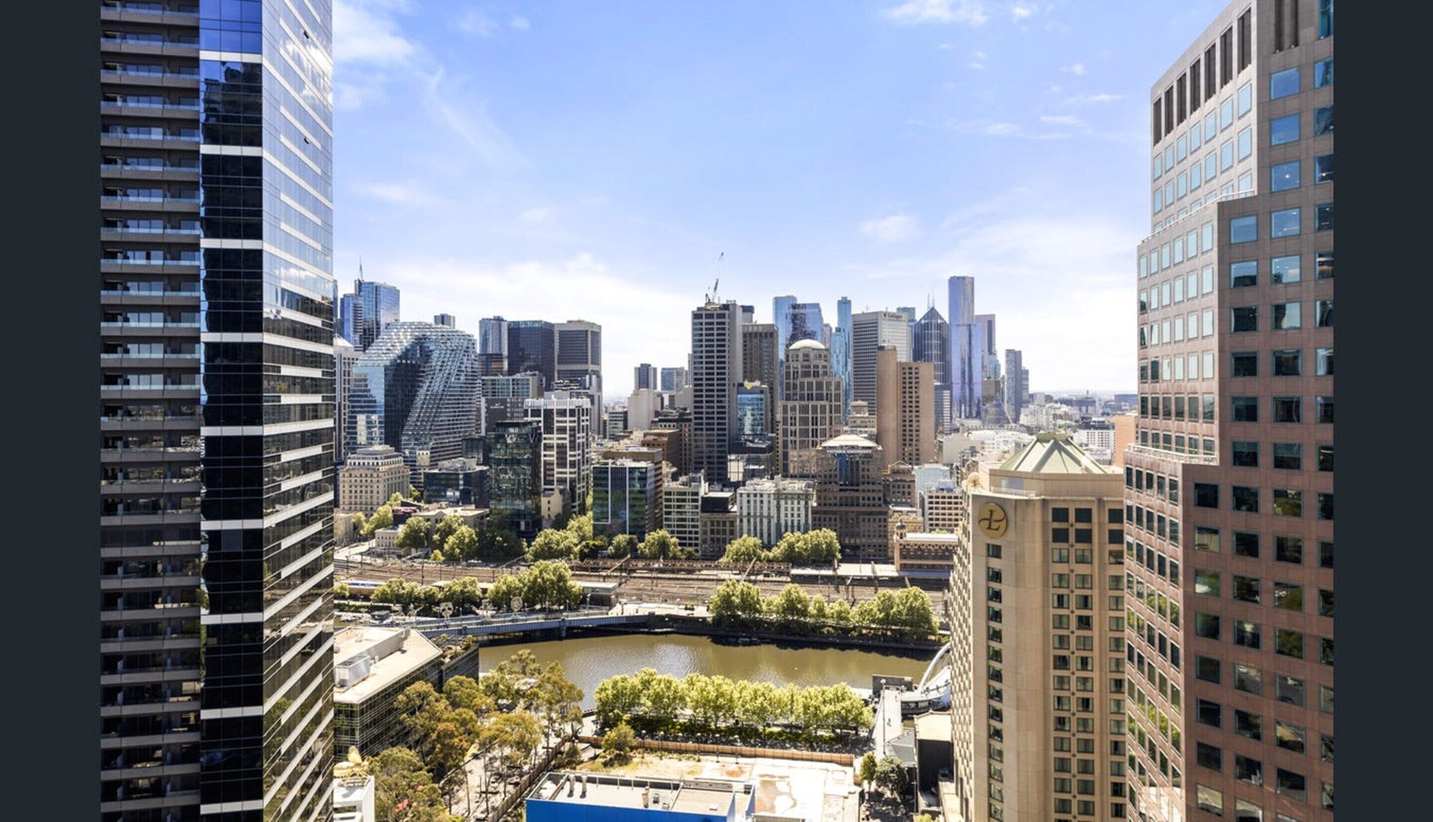 A cityscape with modern high-rise buildings, a river, and a bridge.