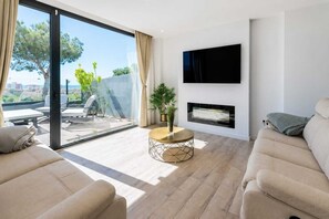 Una sala de estar moderna con un sofá, una mesa de centro, un televisor montado en la pared y una chimenea.