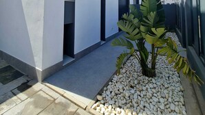 Um edifício moderno com fachada branca, uma planta grande e um jardim de pedras.