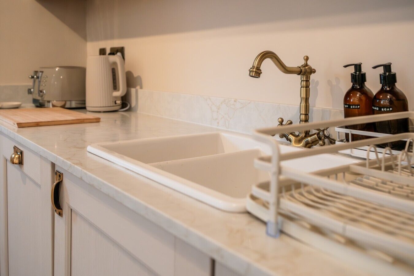 A kitchen with a white sink, a coffee maker, and two soap dispensers on the counter.