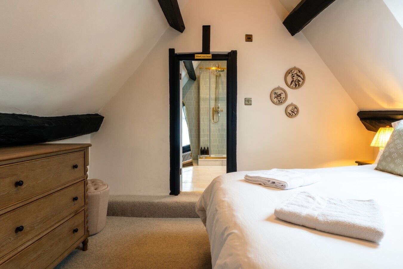 Une chambre à coucher comprenant un lit, une commode, un miroir et une porte donnant accès à une salle de bain.