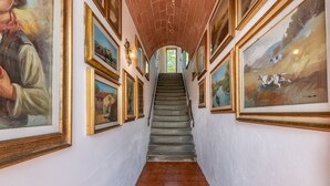 Eine Treppe mit Kunstwerken an beiden Seiten, die zu einem Raum mit Ziegeldecke führt.