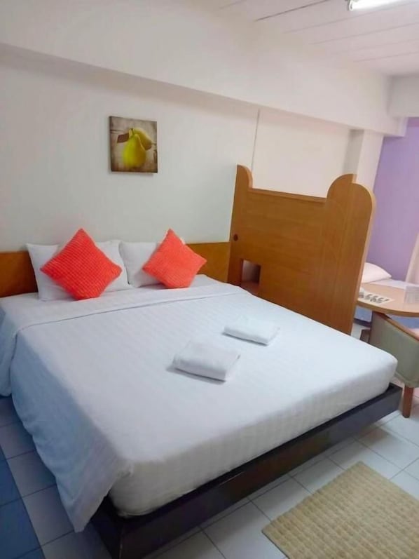 A bed with white bedding, two red pillows, and a wooden headboard. - Bella B Plus Hotel (Bangkok)