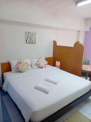 A neatly made bed with white linens and floral pillows, a wooden headboard, and a wall-mounted artwork. - Bella B Plus Hotel (Bangkok)