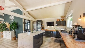 Una cocina moderna con una isla de mármol, encimera de madera y electrodomésticos de acero inoxidable.