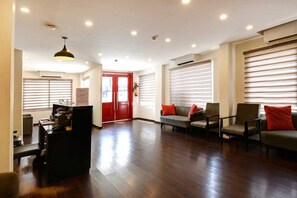 A spacious lobby with a reception desk, seating area, and large windows with blinds. - Classic Neelkanth (Ahmedabad)