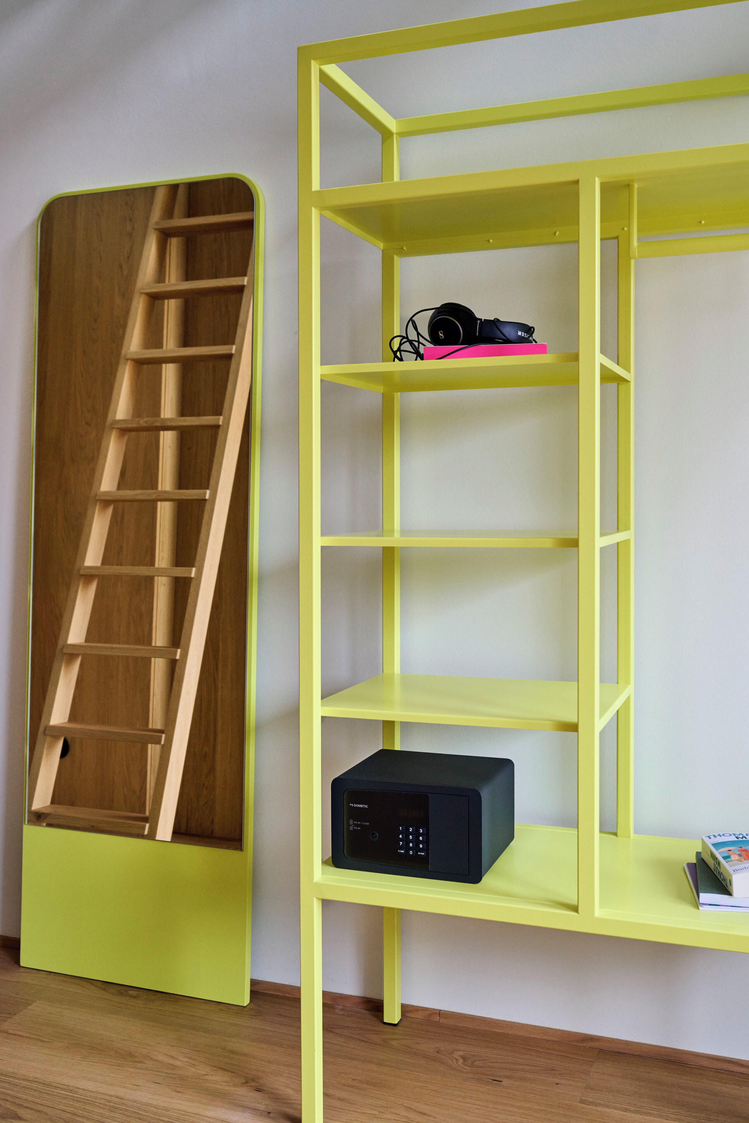 Ein Zimmer mit einer Holzleiter, einem gelben Regalschrank und einem schwarzen elektronischen Gerät.