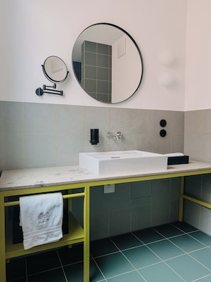 A bathroom with a white sink, a mirror, and a towel rack.