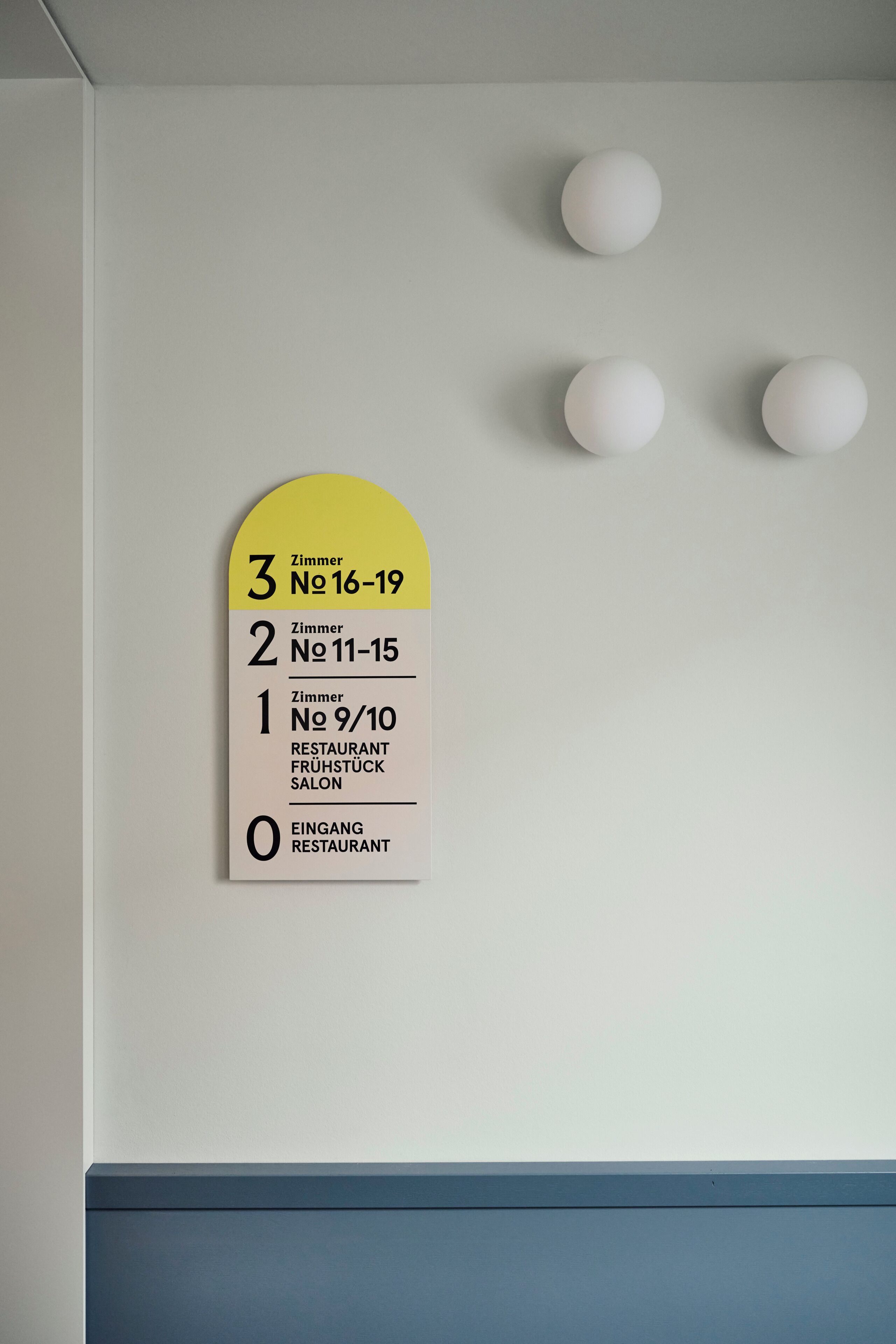Seinälle kiinnitetty kyltti, jossa on huoneiden numerot ja ravintolan tunnus.
