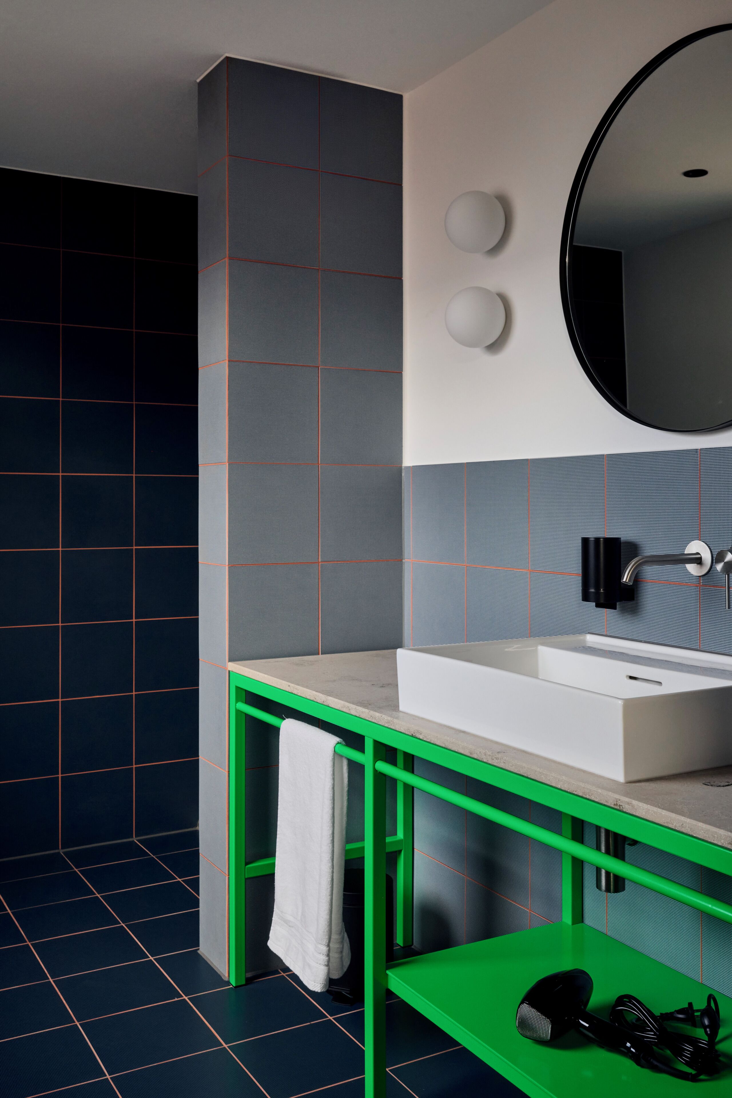 Un baño con un lavabo blanco, un espejo y un estante verde con una toalla y un secador de pelo.