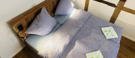 Un lit avec une couvre-lit à carreaux, des oreillers et une tête de lit en bois.