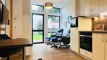Een moderne keuken met houten vloeren, een eethoek met een tafel en stoelen, en een zithoek met een bank en fauteuils.