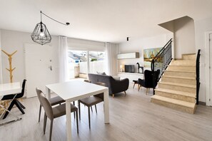Ein modernes Wohnzimmer mit Essbereich, einer Treppe und Blick ins Freie.