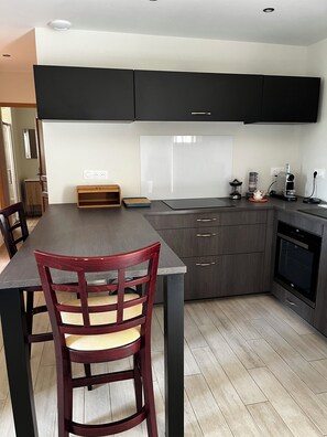 Una cocina moderna con armarios oscuros, una mesa de comedor de madera y un horno empotrado.