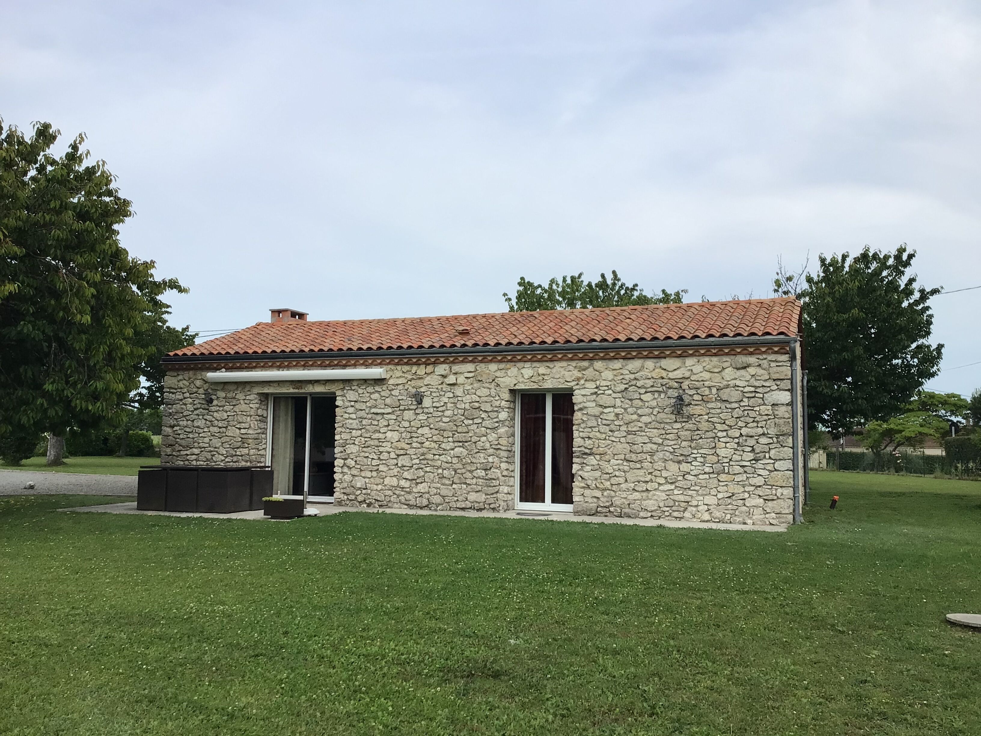 Un bâtiment en pierre avec un toit en tuiles, deux fenêtres et un petit porche.
