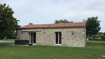 Un bâtiment en pierre avec un toit en tuiles, deux fenêtres et un petit porche.