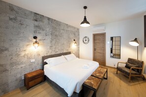 Een slaapkamer met een bed, nachtkastjes, een houten bankje, een stoel, een klok en wandlampen.