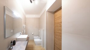 A modern bathroom with a large mirror, a sink, a toilet, and a wooden panel wall. - New TENUTA MARELLA Farmstay, nestled in the countryside just outside Rome (Lazio)