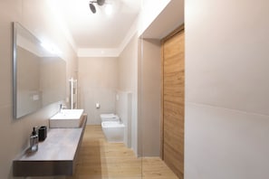 Ein modernes Badezimmer mit einem großen Spiegel, einem Waschbecken, einer Toilette und einer Wandverkleidung aus Holz.